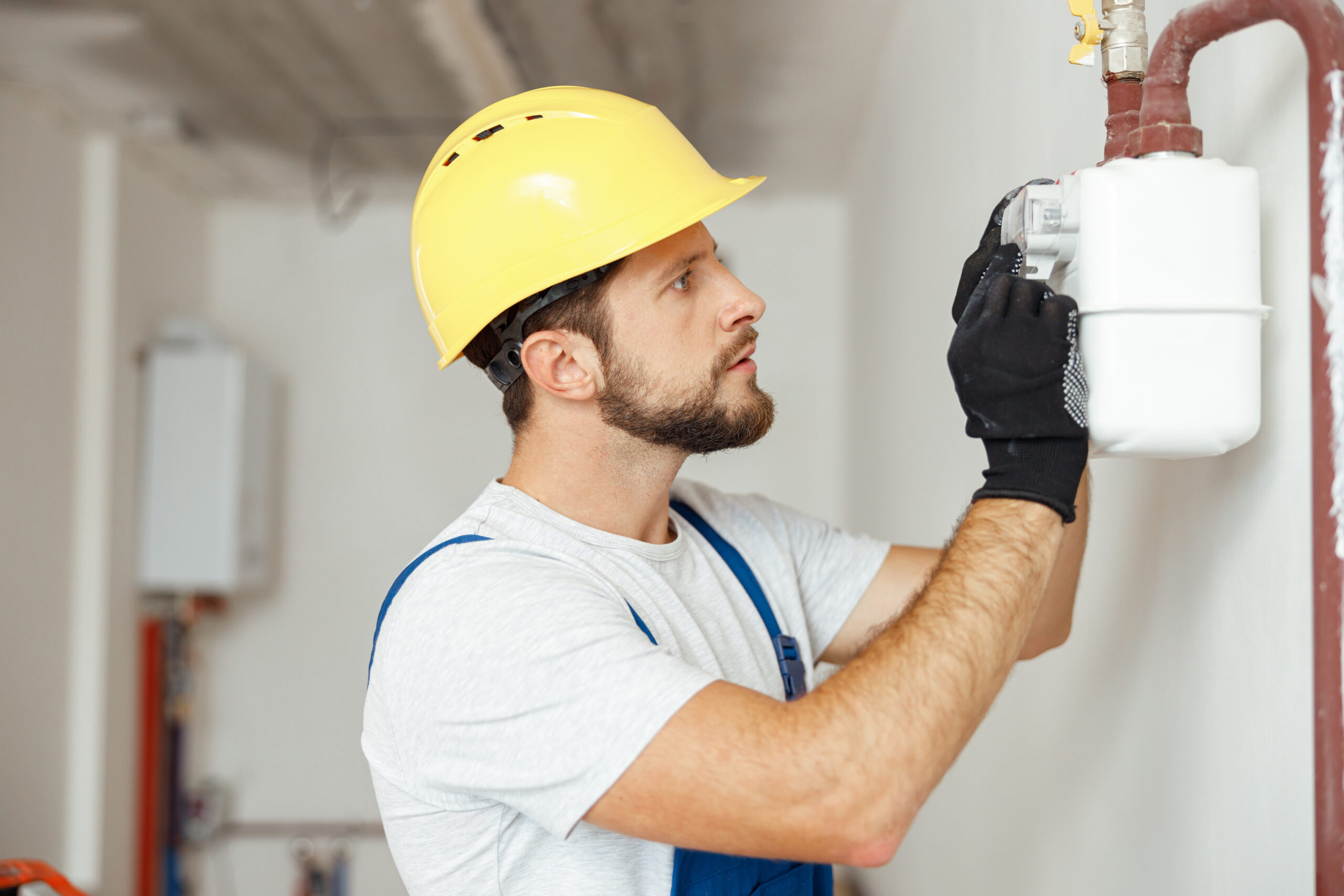 Focused professional heating fitter checking gas consumption at gas pipe and meter counter